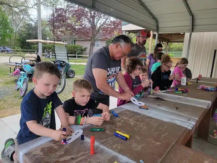 A group of children are making crafts at a spacious table during themed weekends.