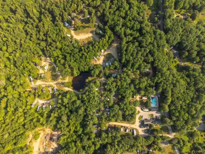 Aerial view of a campground surrounded by dense forest with scattered RVs