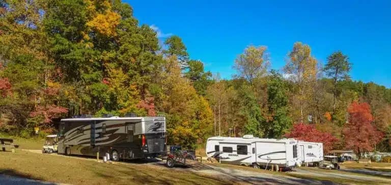 Rv park with rvs parked in a wooded area near a Hidden Creek.