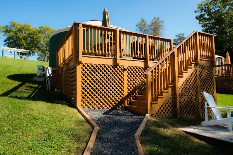 A wooden deck with stairs leading up to a yurt.
