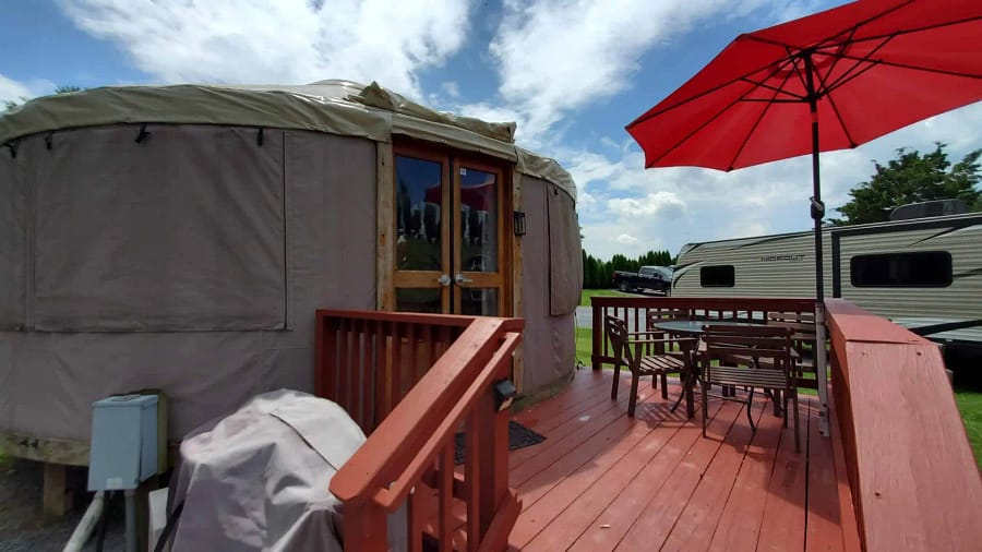 A yurt sitting on a deck with an umbrella.