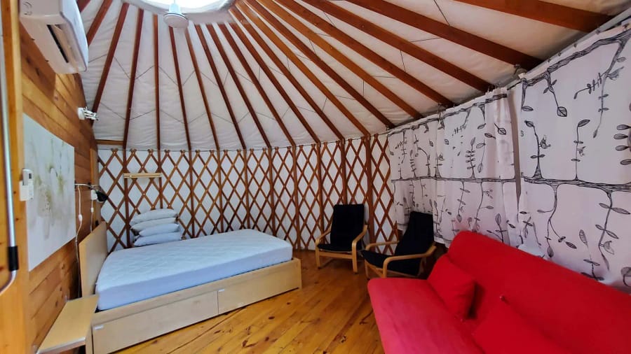 A room with a bed and chairs in a yurt.