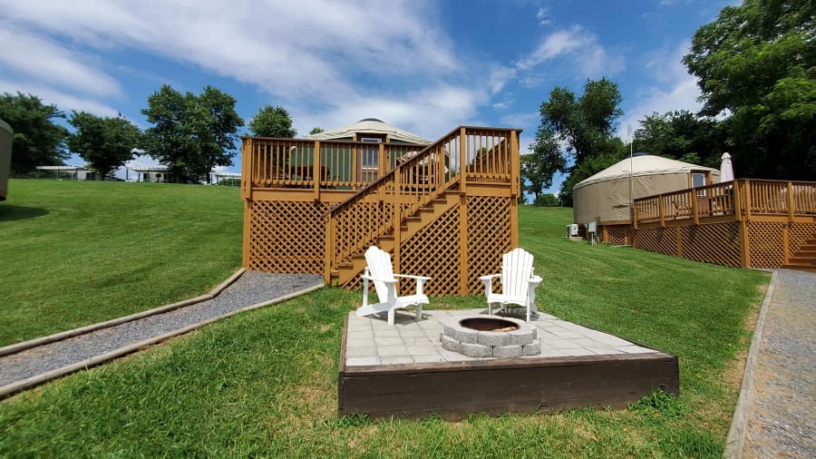 A deck with a fire pit and chairs in the grass.