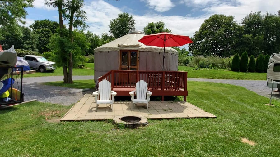 A yurt with chairs and a red umbrella.