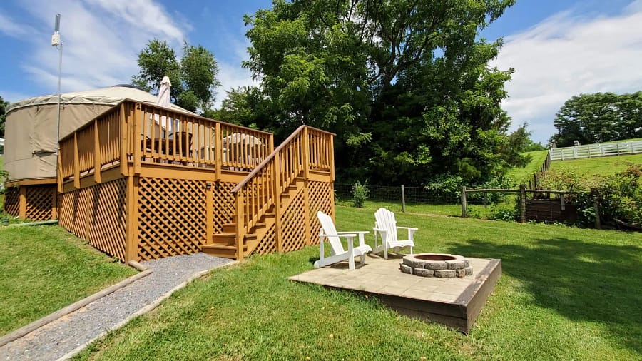 A deck with a fire pit and chairs.