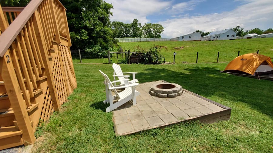 A patio with chairs and a fire pit in the grass.