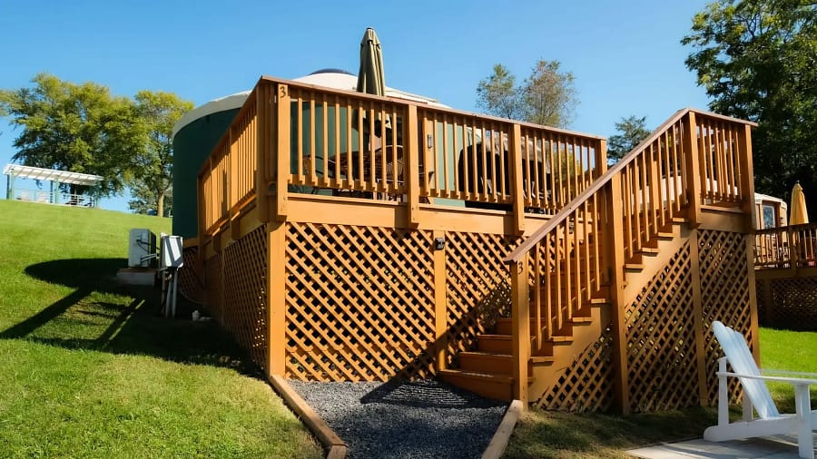 A wooden deck with stairs leading up to a yurt.